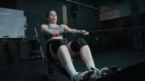 Focused Woman Working Out on Rowing Machine at Gym