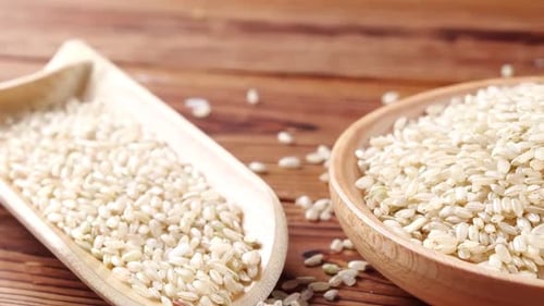 Uncooked Rice in Wooden Bowl with Wooden Spoon