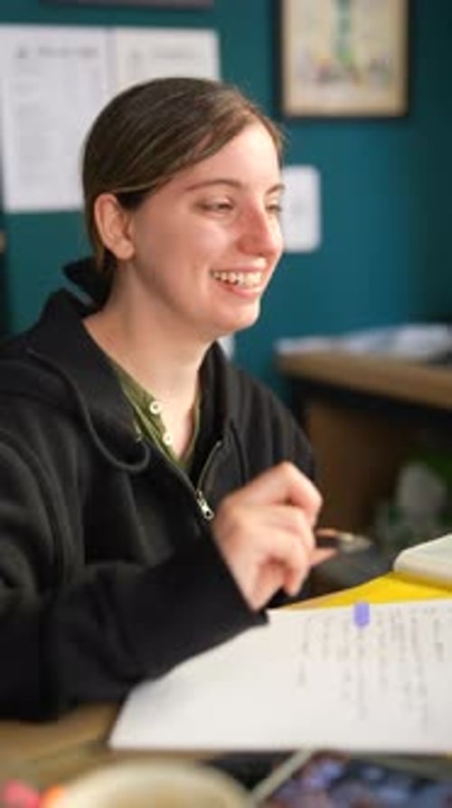 Woman with Cheerful Expression Writing Notes at Desk in Office Displaying Focus and Productivity