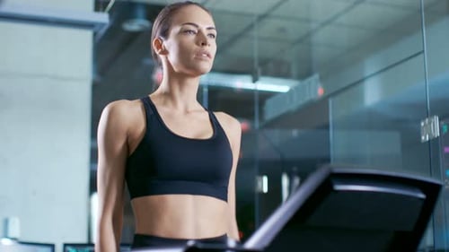 Woman walks on treadmill in indoor gym setting