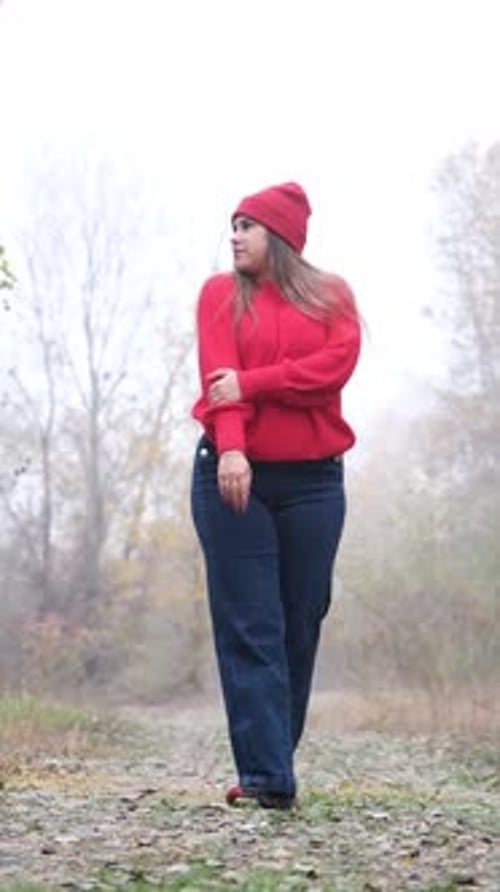 woman in knitted sweater walking in the autumn forest