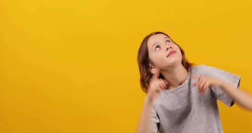 Child Gesturing Upward on Yellow Background