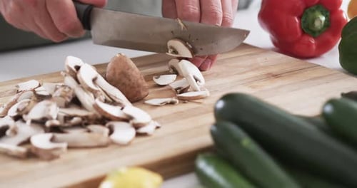 Close-up of hands chopping mushrooms on a cutting board in a home kitchen