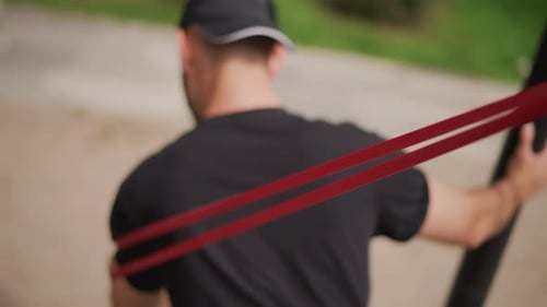 Young Man Exercising with Resistance Band Outdoors
