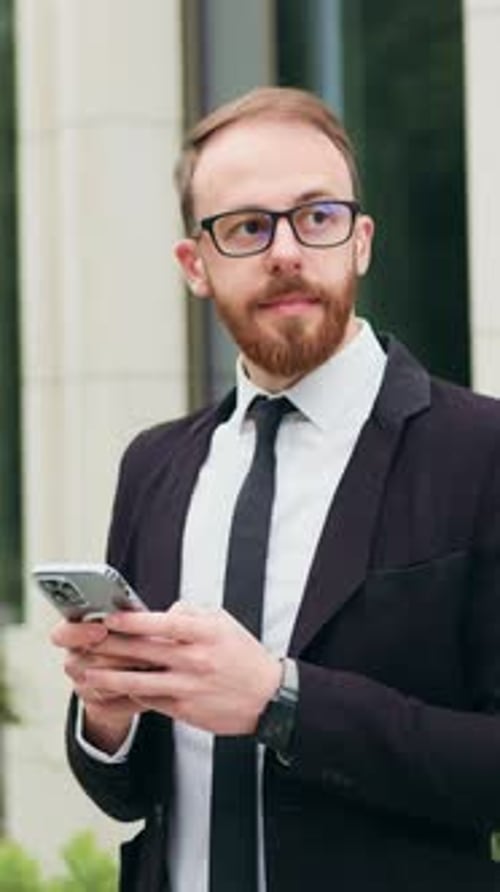 Successful Young Businessman Stading Near Building Office After Workday Using Mobile Phone to Make a