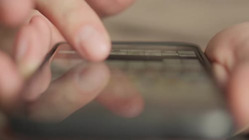 The Closeup Photo Depicts Hands Using a Smartphone Indoors Interacting with Various Apps and