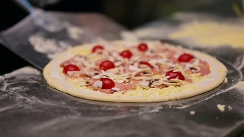 Pizzeriameister, der Pizza zubereitet. Der Koch zieht mit dem Pizzaspatel Pizza am Ofen.