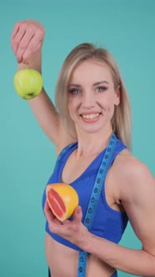 Smiling Woman Holds Apple and Grapefruit for Healthy Diet