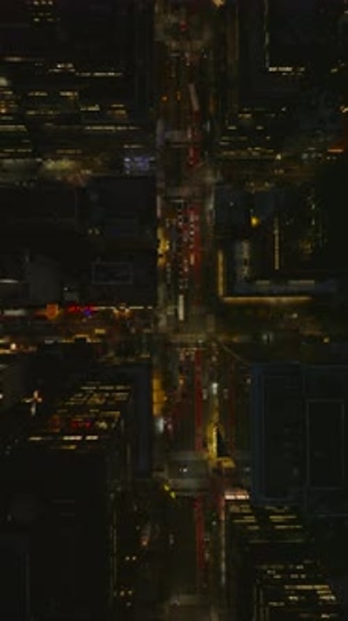Vertical Footage Captures a Camera Gliding Down a Lively Manhattan Street at Night in Slow Motion