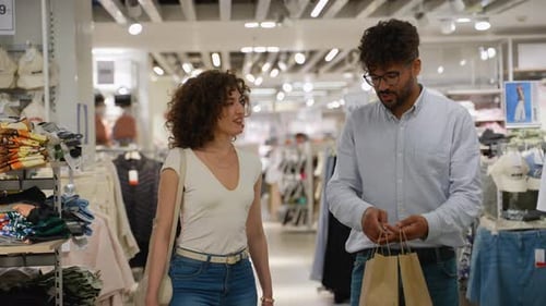 Couple Shopping in Clothing Store Chatting and Holding Shopping Bags