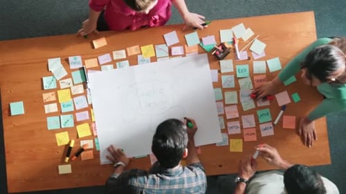Group Brainstorming Around Table Covered in Sticky Notes