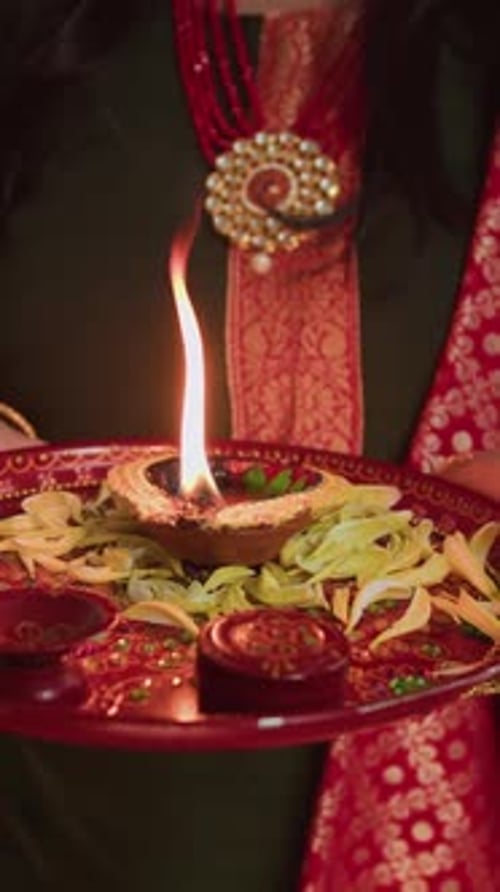 Woman Holds Tray with Lit Oil Lamp, Close-Up