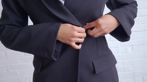 Woman in black trench coat and white scarf buttoning coat, white background
