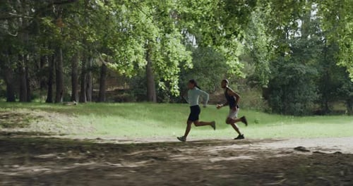Two fit athletes running and jogging in the park or forest outdoors