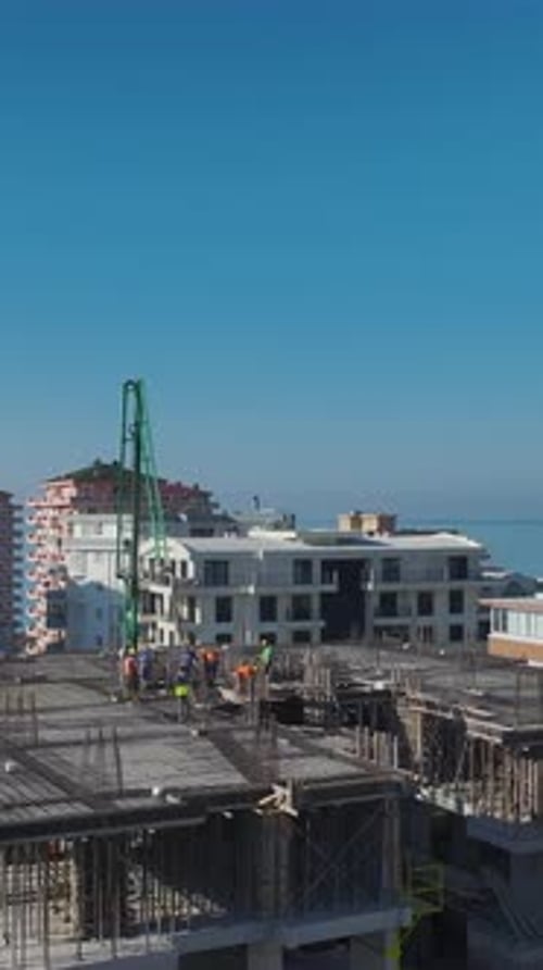 Vertical Video of Engineers Checking Blueprints While Workers Lay Foundations and Assemble Walls