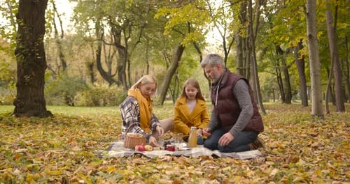 Family Having Picnic in Autumn Park Together