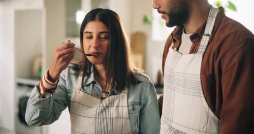 Young Couple Cooking and Tasting Food at Home