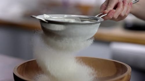 Harina tamizando en cámara lenta con un elegante fondo de cocina de 100 fps de primer plano
