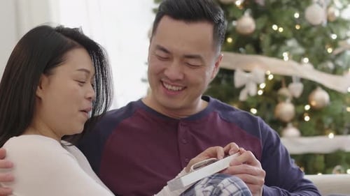Smiling couple opening gift together at Christmas time