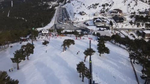 Aufwärts neigbare Luftaufnahme, die eine Skistation in einem verschneiten Tal zeigt. Leute fahren Ski.