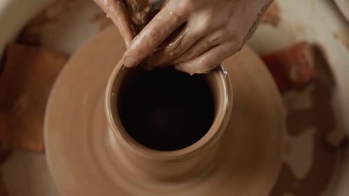 Homme potier travaillant sur une roue de potier fabriquant un vase en céramique à partir d'argile, vue de dessus