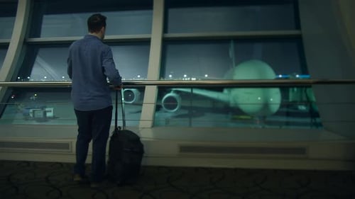 Um viajante está esperando pacientemente no aeroporto com sua bagagem ao lado de um avião