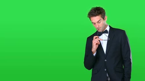 Vídeo de alta definição de um jovem bonito em um smoking profundamente pensado contra uma tela verde