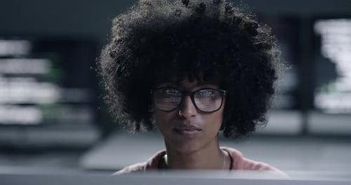 Woman Smiling Removes Glasses in Front of Computers