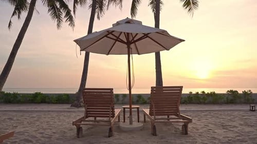 Resort beach chairs and sun umbrella close to seashore at sunset. Static