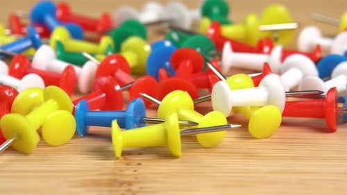 Colorful push pins rotating on the table macro. Drawing pins for marking on the map of the Earth