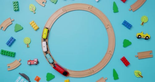 Spielzeugeisenbahn aus Holz mit Autos, die auf einer runden Eisenbahn auf blauem Hintergrund fahren