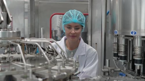 Arbeiterin überprüft Wasserqualität und Flasche an der Produktionslinie, Trinkwasserfabrik