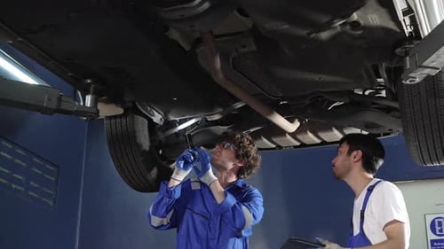 Mechanic inspecting under repairing car at auto repair shop