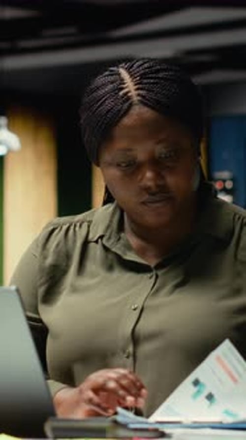 Woman Reviews Charts and Graphs on Laptop in Office