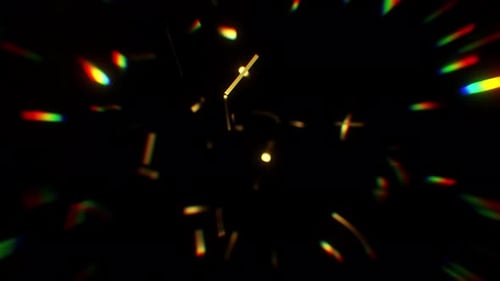 Falling Gold Confetti with soft focus rainbow color rays of light.