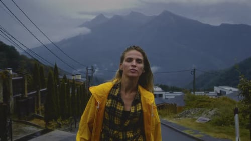 Woman Walks Confidently in Mountain Village in Raincoat