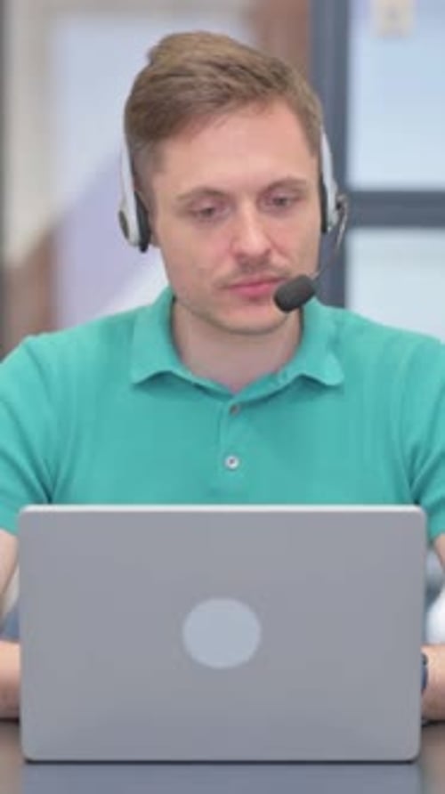 Mature Adult Man with Headset Working on Laptop in Call Center