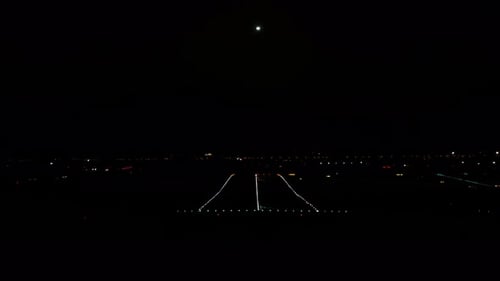 Time lapse of an airport runway with light trails of jets taking off and landing at night