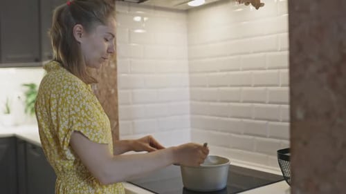 Woman Cooking Food on Stovetop in Modern Kitchen