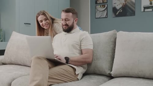 Man Working on Laptop with Woman Watching