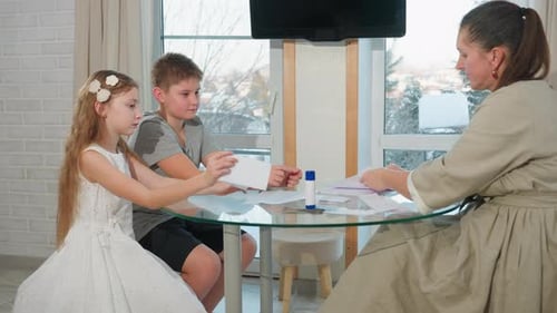 Kids and Teacher Creating Craft with White Paper and Glue on Table at Home