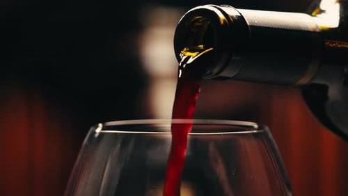 Orange or Red Wine Bottle and Glass Against a Sunset in a Peaceful Vineyard Pouring of Ecological