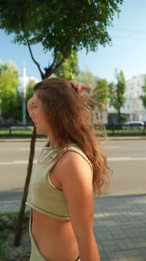 With Her Vibrant Red Curls a Beautiful Girl Enjoys an Evening Stroll Through the Sunny City