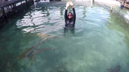 Woman Swimming With Sharks in Tropical Water