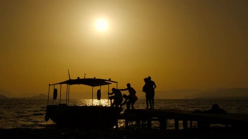 Silhouetted People Gather on Dock at Sunset