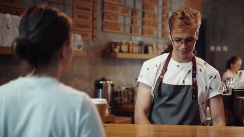 Female customer buying fresh drink in cafe and paying by credit card