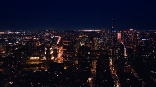 Vast night cityscape of modern metropolis lit with millions of lights. Drone footage above New York