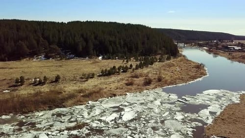 A Beautiful and Serene Winter Landscape Featuring a Tranquil River with Ice Melting Away Stock Clip