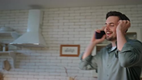 Man Dancing with Phone and Headphones in Kitchen
