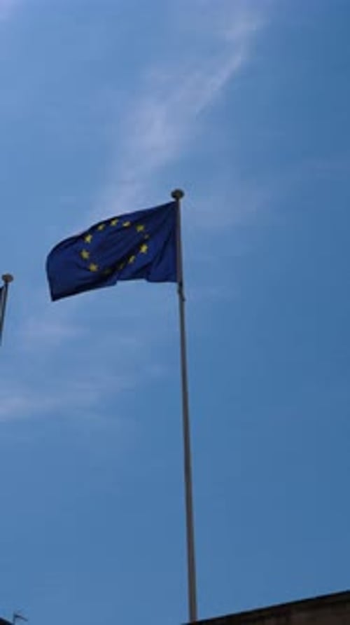 the European flag waving in the air with a blue sky in the background,